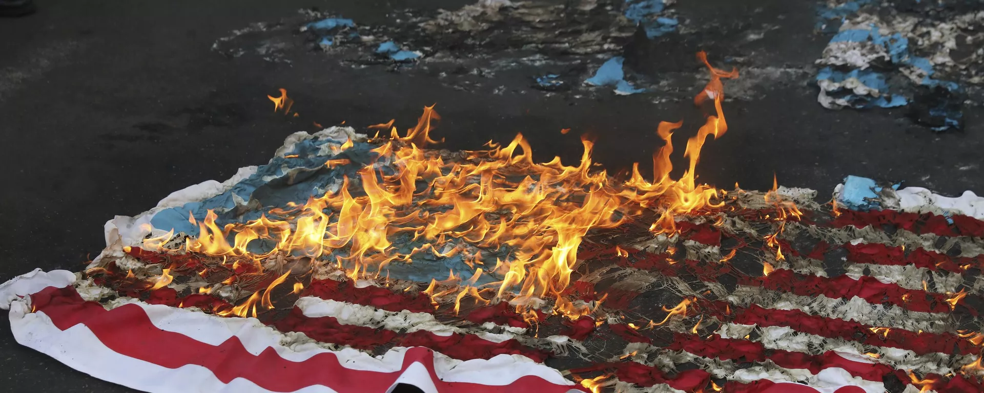 Bandeira dos EUA improvisada é incendiada por manifestantes durante um comício em frente à antiga Embaixada dos EUA em comemoração ao aniversário de sua apreensão de 1979 em Teerã, Irã, em 4 de novembro de 2021 - Sputnik Brasil, 1920, 19.02.2026