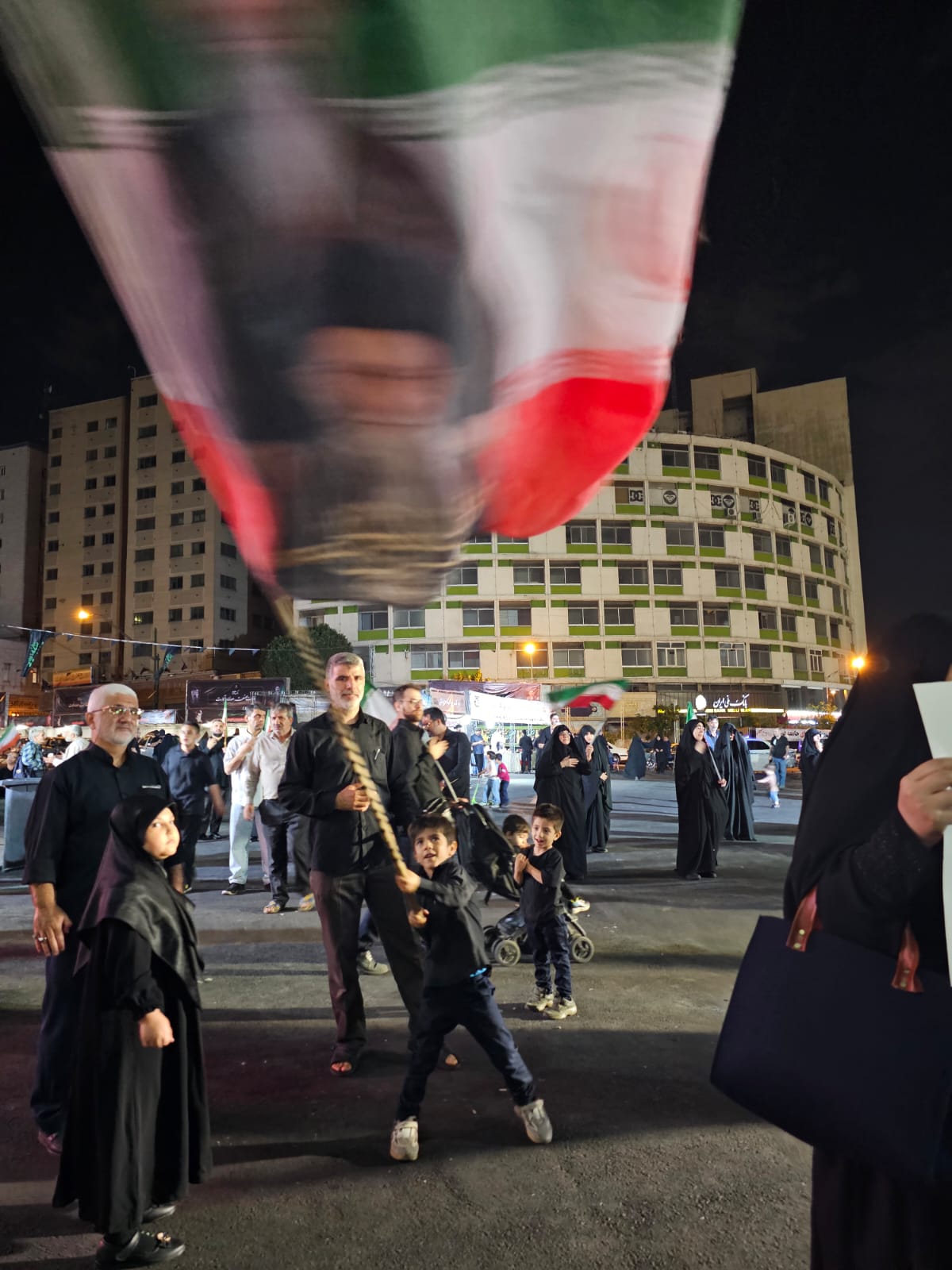 Irã: a guerra das crianças 3 Irã-a-guerra-das-crianças-Criança-balança-bandeira-de-mastro-homenageando-o-aiatolá-Ali-Khamenei-em-Teraã–Foto-Laura-Capriglione-TVT-News